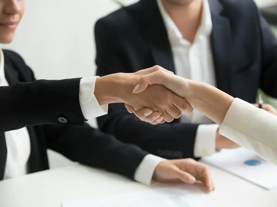 Apretón de manos entre dos personas al cerrar una reunión de trabajo