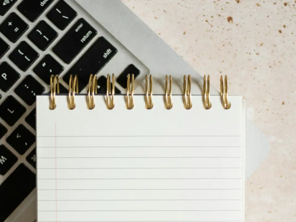 Libreta en blanco apoyada sobre el teclado de un portátil