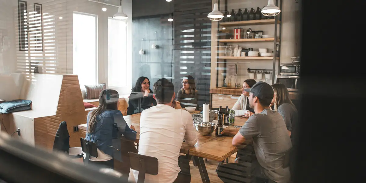 Grupo de compañeros de trabajo conversando alrededor de una mesa en la oficina
